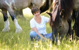 Katharina Hülsken sitzt im Gras zwischen ihren Pferden – pferdegestütztes Coaching für Führungskräfte und Teams im Münsterland